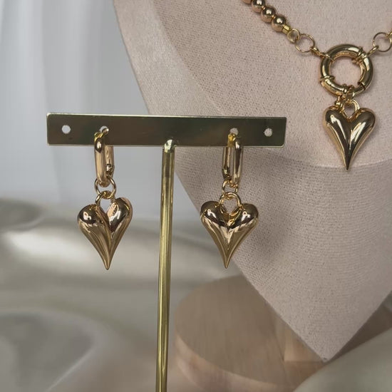 Golden crystal heart jewelry set styled on fabric with flowers and decor