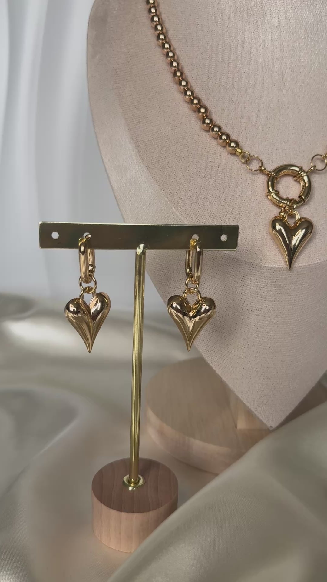 Golden crystal heart jewelry set styled on fabric with flowers and decor